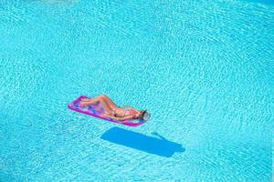 jovem em colchão de ar de biquíni na grande piscina foto