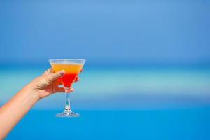 mulher segurando cocktail na praia tropical foto