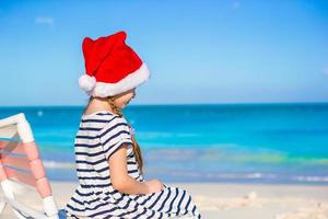 menina adorável usando chapéu de Papai Noel na praia do Caribe foto