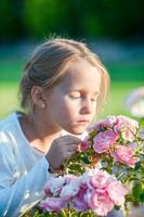 menina adorável cheirando flores coloridas ao ar livre foto