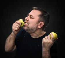 homem com apetite comendo uma maçã verde foto