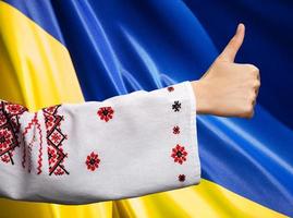 mulher em roupas ucranianas mostra símbolo ok contra a bandeira ucraniana foto