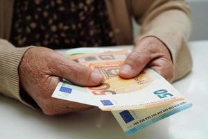 idosa aposentada segurando dinheiro de notas de euro e se preocupa com despesas mensais e pagamento de taxas de tratamento. foto