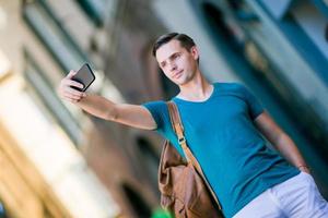 turista caucasiano com smartphone nas mãos caminhando pelas ruas desertas italianas em roma. jovem rapaz urbano de férias explorando a cidade europeia foto