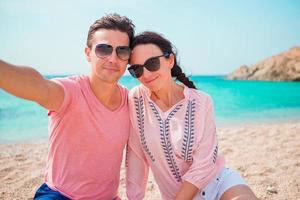 casal de selfie tirando fotos na praia em cyclades. pessoas de turistas tirando fotos de viagens com smartphone nas férias de verão.