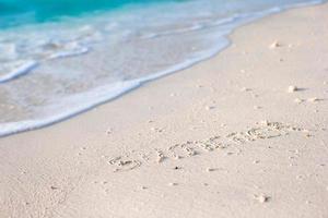 conceito de verão de férias. a palavra verão escrita na areia foto
