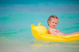 adorável menina brincando em águas rasas na praia branca foto