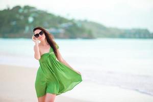 jovem mulher bonita se divertindo na praia tropical. garota feliz andando na praia tropical de areia branca foto