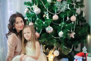 família og mãe e filha perto da árvore de natal na véspera de natal foto