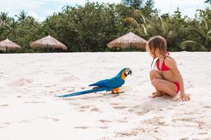 adorável menina na praia com papagaio colorido foto