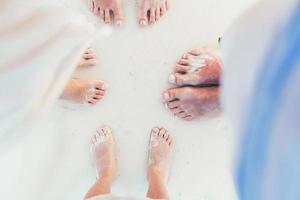 close-up dos pés da família na praia de areia branca foto