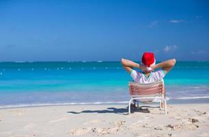 jovem de chapéu de Papai Noel durante as férias na praia foto