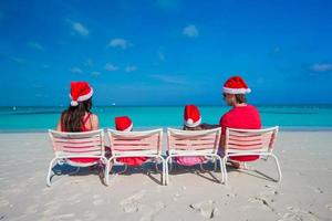 família feliz de quatro pessoas em chapéus de natal durante as férias tropicais foto