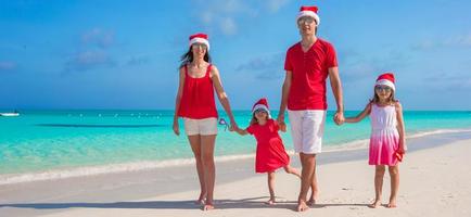 família feliz de quatro pessoas em chapéus de natal durante as férias tropicais foto