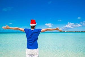 jovem de chapéu de Papai Noel na praia tropical foto