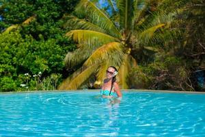 jovem mulher bonita desfrutando de uma piscina tranquila de luxo foto