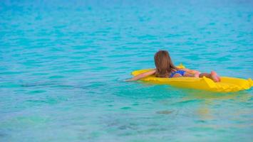 menina adorável no colchão inflável de ar no mar foto