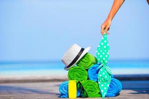 conceito de acessórios de praia e férias de verão - close-up de toalhas coloridas, chapéu, bolsa e protetor solar foto