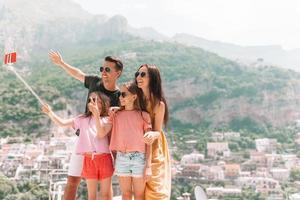 pais e filhos tirando selfie foto fundo cidade de positano em itali na costa de amalfi