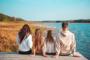 linda família no dia quente de outono perto do lago foto