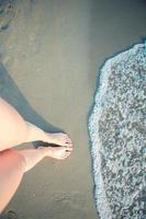 belas pernas lisas das mulheres na praia de areia branca foto