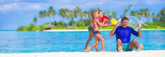 adoráveis meninas se divertindo com o pai na praia branca foto