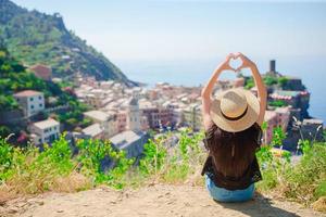 linda garota fazendo com as mãos em forma de coração no antigo fundo da cidade costeira de vernazza, parque nacional de cinque terre, ligúria, itália, europa foto