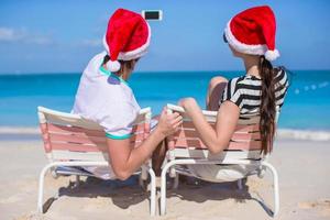 jovem casal feliz em chapéus de papai noel vermelhos tirando uma foto