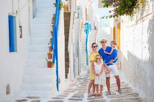 férias em família na pequena e velha cidade grega. pais e filhos na rua da aldeia tradicional grega na ilha de mykonos foto