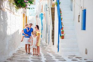 férias em família em pequena cidade europeia. pais e filhos na rua da aldeia tradicional grega na ilha de mykonos foto