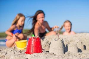 mãe e adoráveis filhas brincando com brinquedos de praia foto