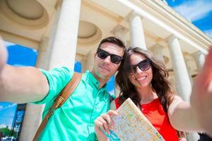 jovens amigos turistas viajando de férias na europa sorrindo felizes. família caucasiana com mapa da cidade fazendo fundo selfie de atrações foto