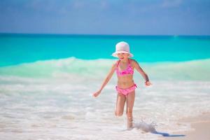 adorável menina na praia se divertindo muito em águas rasas foto