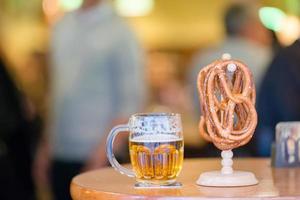 feche pretzels macios salgados e cerveja em fundo de madeira. foto