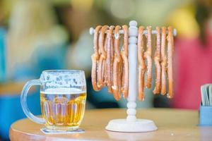 feche pretzels macios salgados e caneca de cerveja light em fundo de madeira. foto