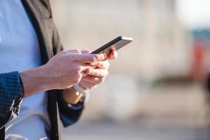 closeup de mãos masculinas está segurando o celular ao ar livre na rua. homem usando smartphone móvel. foto