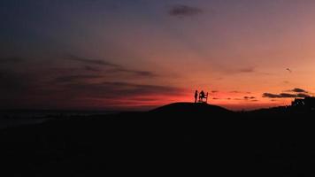 silhueta de 2 pessoas em pé na colina durante o pôr do sol foto