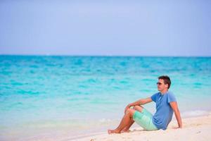 jovem curtindo a música na praia de areia branca. turista feliz relaxando nas férias tropicais de verão. foto