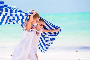 meninas se divertindo correndo com toalhas na praia tropical. as crianças aproveitam as férias de verão em família no oceano índico foto