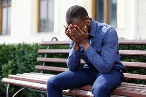 homem cansado senta no banco do lado de fora foto