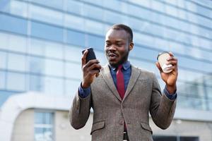 homem com um café lendo em seu telefone foto