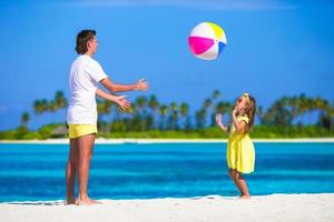 feliz pai e filha correndo na praia com bola se divertindo juntos foto