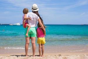 jovem mãe e duas filhas na praia exótica em dia ensolarado foto