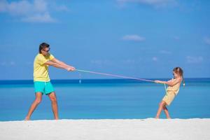 feliz pai e sua adorável filha na praia tropical se divertindo foto