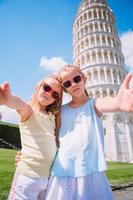 pisa - viaje para lugares famosos na europa, retrato de garotas ao fundo a torre inclinada em pisa, itália foto