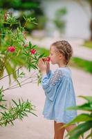 menina adorável cheirando flores coloridas no dia de verão foto