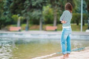 jovem mulher feliz andando perto do lago no dia quente de outono foto