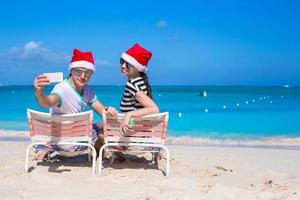 jovem casal de chapéu de Papai Noel aproveita as férias na praia foto