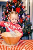 adorável menina assando biscoitos de gengibre de natal foto