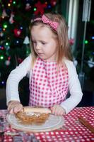 menina adorável com rolo assando biscoitos de gengibre para o natal foto